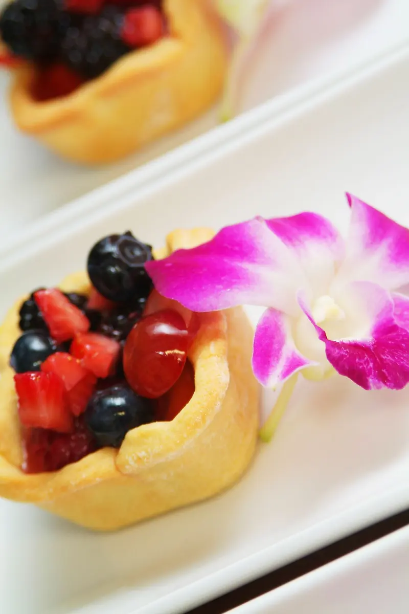 Mini fruit tarts with fresh berries and an orchid garnish